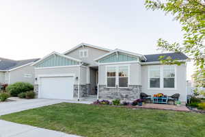 Craftsman house featuring an attached garage, board and batten siding, driveway, and a front lawn