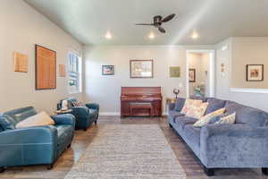 Living room featuring a ceiling fan, recessed lighting, dark wood-style flooring, and baseboards