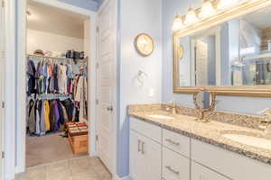 Full bathroom with double vanity, a walk in closet, and tile patterned floors