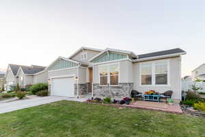 View of front of house with driveway, board and batten siding, an attached garage, stone siding, and stucco siding