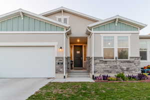 Craftsman inspired home featuring stone siding, a garage, driveway, and stucco siding