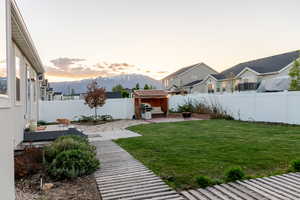 Yard at dusk featuring a patio area, a storage unit, an outbuilding, a deck with mountain view, and a residential view