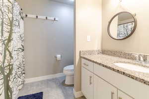Bathroom featuring toilet, vanity, and baseboards