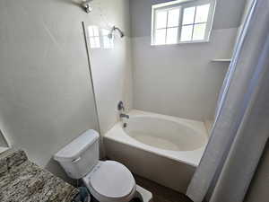 Full bath with toilet, a bath, a shower with shower curtain, and wood finished floors