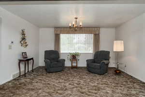Sitting room with a chandelier, carpet floors, and baseboards