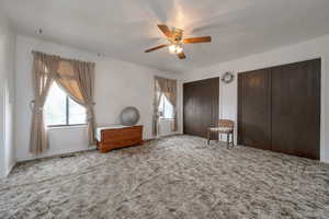 Carpeted bedroom with multiple windows, multiple closets, and a ceiling fan