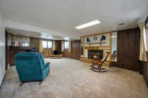Living area with wooden walls, a glass covered fireplace, and light carpet