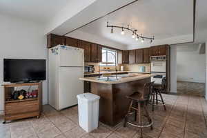 Kitchen with white appliances, dark brown cabinetry, light countertops, and a kitchen island