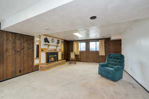 Unfurnished room featuring wooden walls, carpet, and a glass covered fireplace