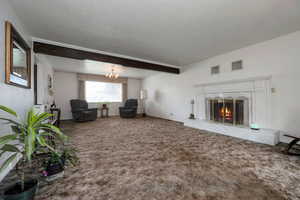 Living room with carpet floors, a chandelier, a premium fireplace, beam ceiling, and baseboards