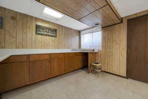 Kitchen featuring wood walls, brown cabinets, light floors, and light countertops
