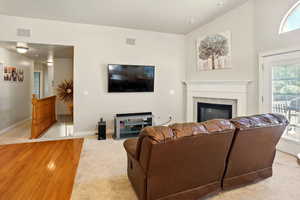 Great room featuring carpet floors, a tile fireplace, baseboards, and vaulted ceiling