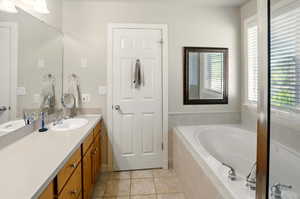 Bathroom with a bath, tile flooring, and vanity