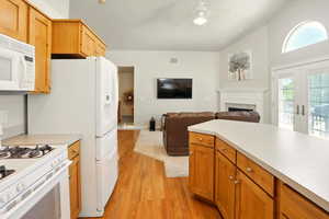 Kitchen featuring white appliances, light wood-style floors, light countertops, a fireplace, and ceiling fan