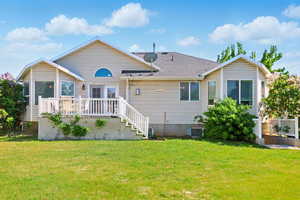 Rear view of property with a wooden deck, a yard, and roof with shingles