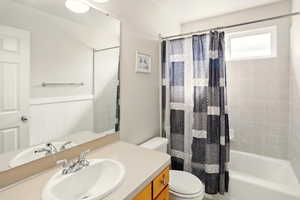 Full bathroom featuring toilet, shower / bathtub combination with curtain, and vanity