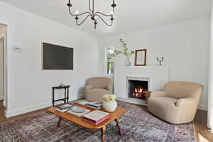 Living room with wood finished floors, baseboards, venetian plastered fireplace surround, and a chandelier