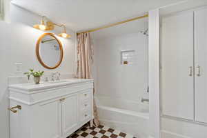 Full bath with shower / bath combo, tile patterned floors, vanity, and a textured ceiling. quartz counters and tile shower walls