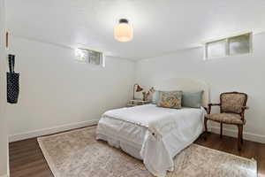 Bedroom featuring baseboards, wood finished floors, and a textured ceiling