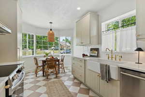Kitchen featuring appliances with stainless steel finishes, tile floors, plenty of natural light, backsplash, and a textured ceiling