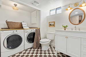 Bathroom featuring washer and clothes dryer, tile patterned floors, laundry chute, vanity, and baseboards