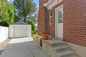 View of side of property featuring fence, driveway, detached garage, and brick siding