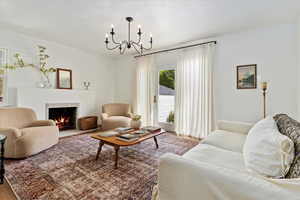 Living area with a chandelier, wood finished floors, venetian plastered fireplace surround.