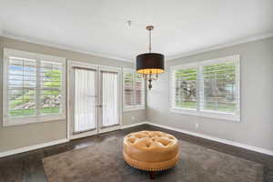 Living area with crown molding, wood finished floors, baseboards, and french doors