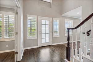 Foyer entrance with crown molding, baseboards, and wood finished floors