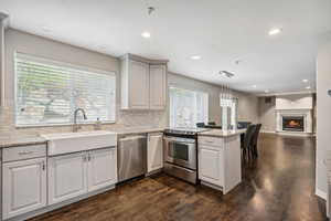 Kitchen with stainless steel appliances, a sink, a peninsula, backsplash, and recessed lighting