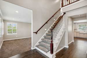 Stairway with baseboards, wood finished floors, recessed lighting, ornamental molding, and carpet floors