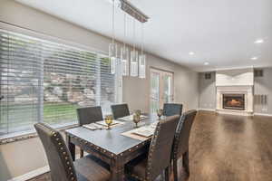 Dining room featuring wood finished floors, baseboards, recessed lighting, and a glass covered fireplace