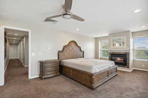 Carpeted bedroom with a fireplace, baseboards, a ceiling fan, and recessed lighting