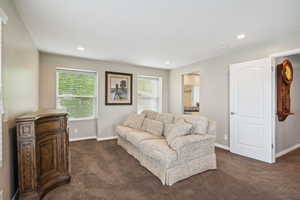 Living room featuring dark colored carpet, baseboards, and recessed lighting