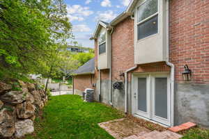 Back of property with a lawn and brick siding