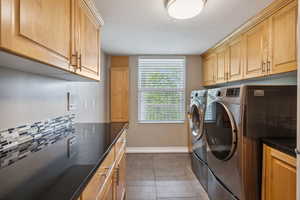 Laundry room featuring separate washer and dryer, cabinet space, and baseboards