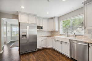 Kitchen with appliances with stainless steel finishes, a sink, dark wood-style floors, tasteful backsplash, and recessed lighting