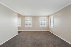 Unfurnished room featuring baseboards, crown molding, dark colored carpet, and recessed lighting