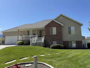 View of front of home featuring brick siding, covered porch, a garage, a front lawn, and concrete driveway