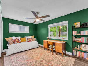 Bedroom featuring wood finished floors, a textured ceiling, baseboards, and ceiling fan