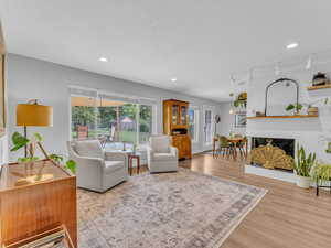 Living area featuring light wood-style flooring, a brick fireplace, rail lighting, and recessed lighting