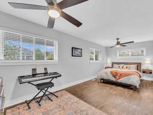 Bedroom featuring wood finished floors, baseboards, and a ceiling fan