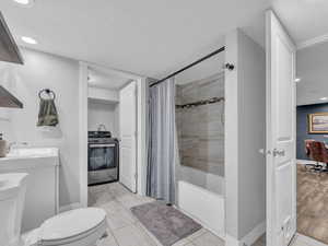 Bathroom featuring a sink, toilet, shower / bath combo with shower curtain, baseboards, and recessed lighting