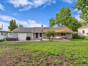 Back of property featuring a hot tub, a patio area, an attached garage, central AC unit, and a chimney