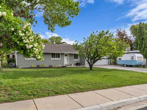 View of front of property with central AC, a front yard, driveway, and a garage