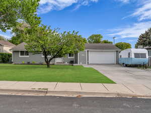 Obstructed view of property featuring a front lawn, driveway, a garage, roof with shingles, and central AC unit