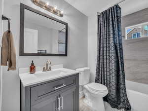 Full bath with toilet, vanity, and shower / bath combo