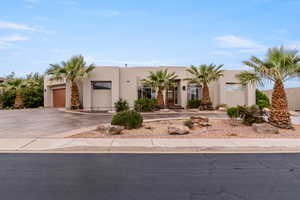 Adobe home featuring an attached garage, concrete driveway, and stucco siding