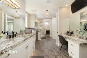 Bathroom featuring a chandelier, baseboards, two vanities, and recessed lighting
