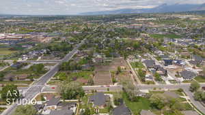 Aerial view of property and surrounding area featuring nearby suburban area and a mountain backdrop